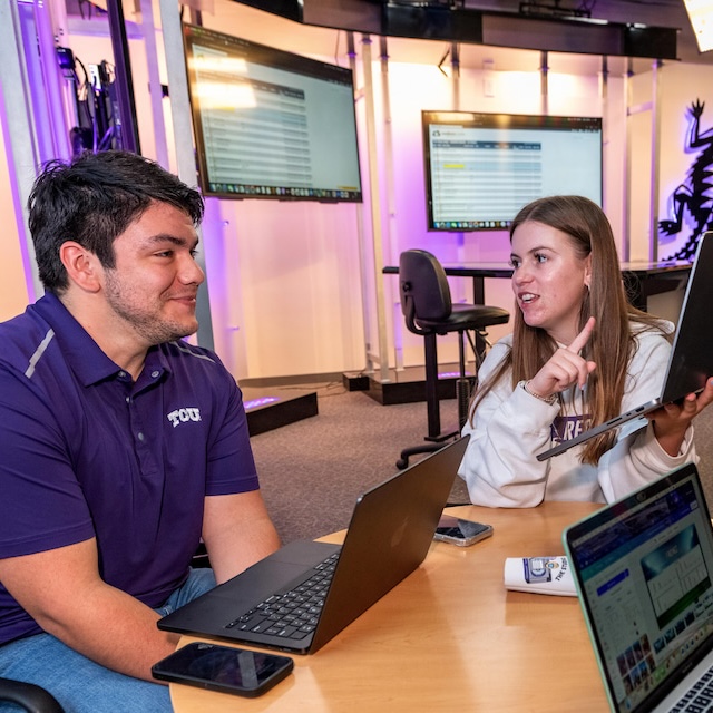 Two students discuss work on laptop