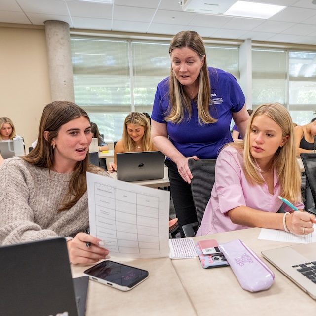 Two students and a faculty member discussing class project