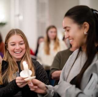 Two students light candles during TCU's annual candlelight service. 