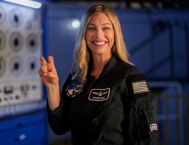 Astronaut Anna Menon holds up Go Frogs sign